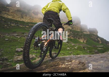 Beine von Radfahrer und Hinterrad Nahaufnahme des hinteren mtb-Bikes in den Bergen vor dem Hintergrund von Felsen bei nebligen Wetter. Die c Stockfoto