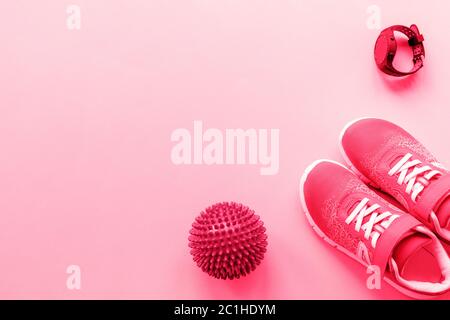 Rote Turnschuhe, Sportuhr und Massageball auf rosa Hintergrund. Konzept für gesundes Leben, Sport und Training, Draufsicht, Flat Lay, Copy Space Stockfoto