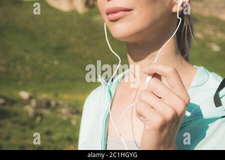 Nahaufnahme der unteren Gesichtsfläche eines jungen Läufermädchens in der Natur vor dem Joggen. Kinn und lächelnde Lippen der Sportlerin und Hand o Stockfoto