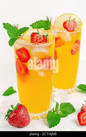 Orange Sommer Cocktail mit Erdbeeren, Zitrone und Eis auf weißem Hintergrund. Stockfoto