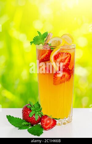 Erfrischender Punsch mit Erdbeeren, Zitrone und Minze auf unscharfem sonnigen Hintergrund. Stockfoto