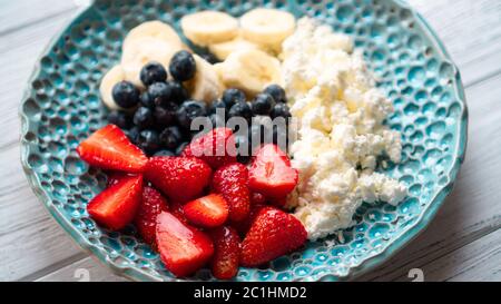 Morgenvergnügen. Gesundes Sommerfrühstück. Hüttenkäse mit Beeren Früchte und Honig. Gemütliches, einfaches Frühstück Stockfoto