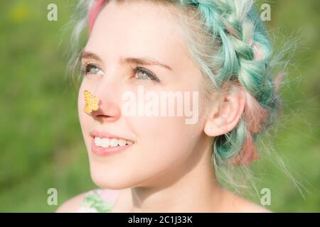 Gelber Schmetterling sitzt auf der Nase nettes junges Mädchen auf der Natur. Harmonie und Genuss in der Natur Stockfoto