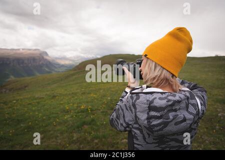 Ein junges Mädchen fotografiert an einem bewölkten Tag ein Plateau auf einem hohen Berg. Blick auf das Mädchen dahinter Stockfoto