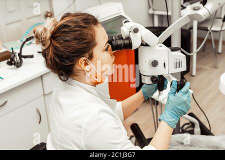 Zahnarzt junge Frau behandelt einen Patienten einen Mann. Der Arzt verwendet Einweghandschuhe, eine Maske und einen Hut. Der Zahnarzt arbeitet im Mund des Patienten, verwendet ein Stockfoto