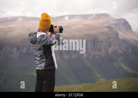 Ein junges Mädchen fotografiert an einem bewölkten Tag ein Plateau auf einem hohen Berg. Blick auf das Mädchen dahinter Stockfoto