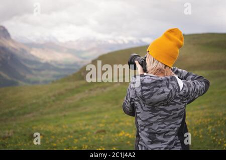 Ein junges Mädchen fotografiert an einem bewölkten Tag ein Plateau auf einem hohen Berg. Blick auf das Mädchen dahinter Stockfoto