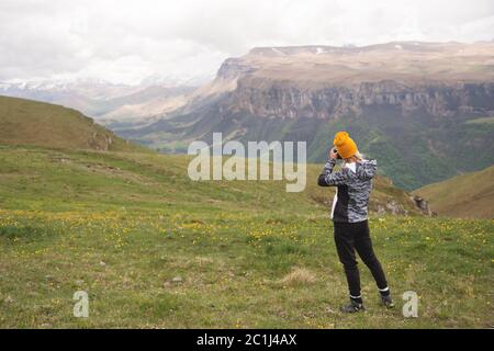 Ein junges Mädchen fotografiert an einem bewölkten Tag ein Plateau auf einem hohen Berg. Blick auf das Mädchen dahinter Stockfoto