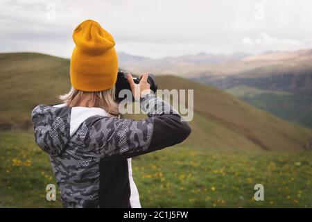 Ein junges Mädchen fotografiert an einem bewölkten Tag ein Plateau auf einem hohen Berg. Blick auf das Mädchen dahinter Stockfoto