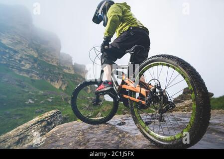 Beine von Radfahrer und Hinterrad Nahaufnahme des hinteren mtb-Bikes in den Bergen vor dem Hintergrund von Felsen bei nebligen Wetter. Die c Stockfoto