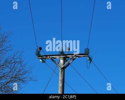 Stromleitungen über Kopf mit Glastrennern und einem klaren blauen Himmel Stockfoto