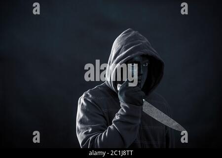 Mit Kapuze Mann mit schwarzer Maske holding Messer im Dunkeln Stockfoto