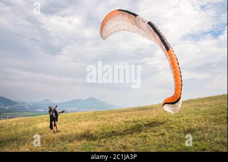 Der Gleitschirm öffnet seinen Fallschirm, bevor er vom Berg im Nordkaukasus abheben kann. Den Fallschirmflügel mit ai füllen Stockfoto