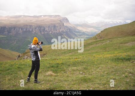 Ein junges Mädchen fotografiert an einem bewölkten Tag ein Plateau auf einem hohen Berg. Blick auf das Mädchen dahinter Stockfoto