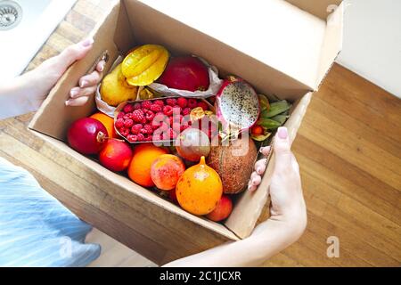 Junge Frau hält eine Schachtel mit Obst und Gemüse in der Küche Stockfoto