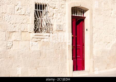 Haus mit roter Tür und traditionellen schwangeren Fensterbars in Mdina, Malta. Stockfoto