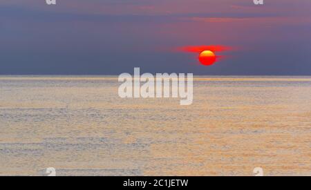 Wunderbarer Sonnenaufgang über einem ruhigen Meer Stockfoto