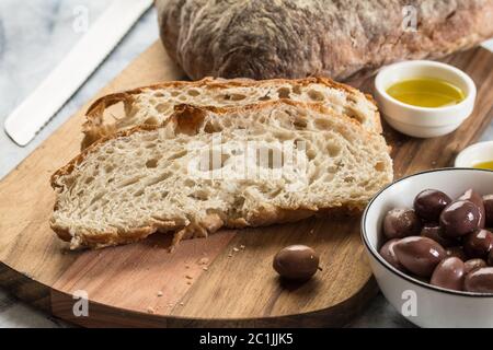 Brotscheiben auf Holzbrett - selektiver Fokus auf italienischen Ciabatta mit Oliven Stockfoto