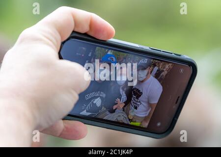 Saint John, NB, Kanada - 14. Juni 2020: Black Lives Matter Rallye. Eine Hand benutzt ein Handy, um ein Selfie einer Gruppe von Menschen zu machen. Stockfoto