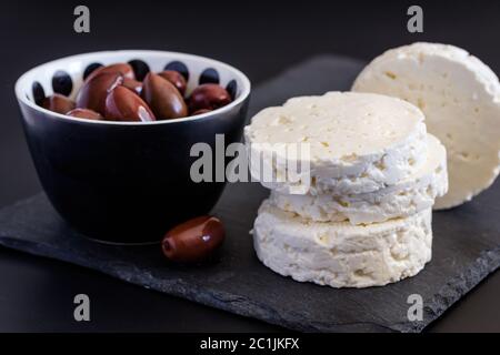 Feta Käse auf schwarzem Schiefer Hintergrund mit Oliven - selektive Fokus auf Käse Stockfoto