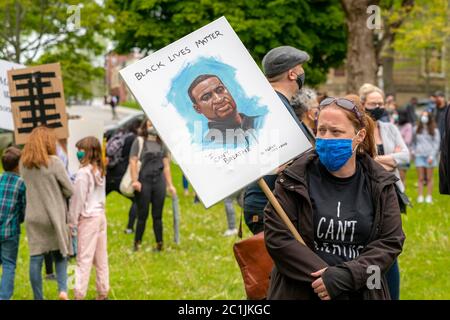 Saint John, NB, Kanada - 14. Juni 2020: Black Lives Matter Rallye. Ein Protestler trägt eine Maske und trägt ein Schild mit einem Bild von George Floyd. Stockfoto