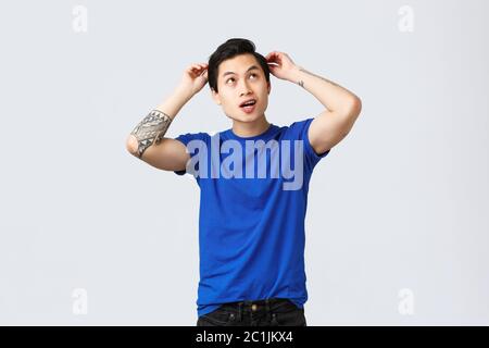 Menschen verschiedene Emotionen, Lifestyle und Casual Konzept. Upbeat gut aussehende asiatische Mann immer bereit Datum, Bürsten Haare, Frisur und suchen nach oben Stockfoto
