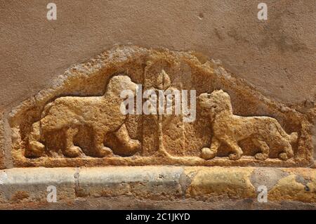 Löwen und ein LIS-Fleur, die an der Wand einer mittelalterlichen Kirche gemeißelt wurden, die von den Tempelrittern in Tomar, Portugal, erbaut wurde. Stockfoto