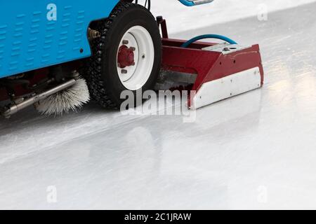 Eisvorbereitung auf der öffentlichen Eisbahn zwischen den Sitzungen am Abend im Freien. Poliertes Eis bereit für Spiel. Eiswartungsmaschine in Nahaufnahme Stockfoto