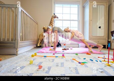 Junge Mutter tut eine Plank Push-up mit Kleinkind Tochter Auf dem Rücken Stockfoto