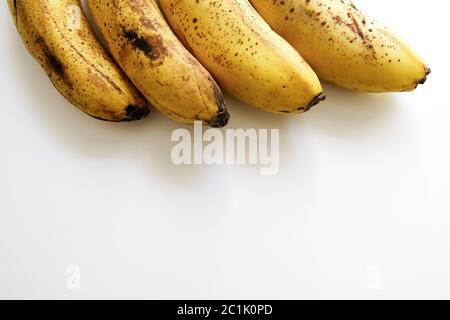 Ein Bündel überreifer Bananen in einer Reihe auf der Oberseite. Unten im Feld für die Kopie ist ein weißer Bereich vorhanden. Gesunde Ernährung in Isolation, um Viren zu verhindern Stockfoto