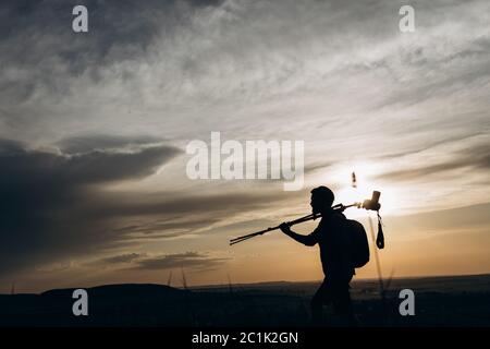 Männlicher Fotograf in Silhouette auf Stativ tragen Stockfoto