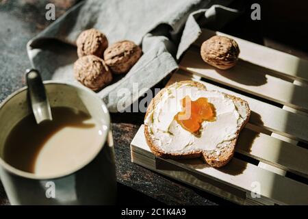 Von oben von leckeren Stück Brot mit Butter und Marmelade auf dem Tisch mit Walnüssen und frischem Kaffee platziert Stockfoto