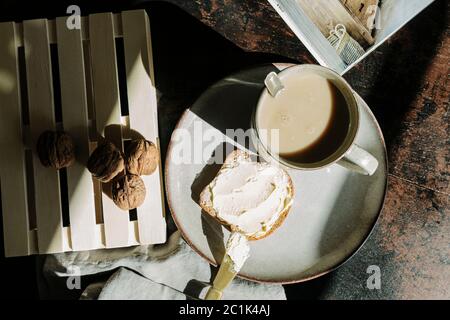 Schuss von oben von leckeren Stück Brot mit Butter und Marmelade auf dem Tisch mit Walnüssen und frischem Kaffee platziert Stockfoto