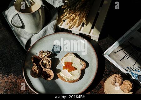 Von oben von leckeren Stück Brot mit Butter und Marmelade auf dem Tisch mit Walnüssen und frischem Kaffee platziert Stockfoto