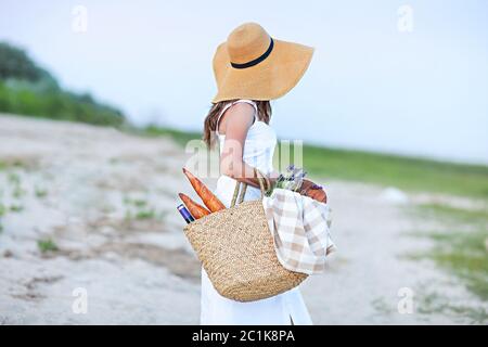 Junge Frau hält Picknickkorb mit Flasche Wein und Baguette Stockfoto