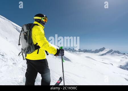 Portrait eines professionellen Freeriders, der auf einer verschneiten Piste vor dem Hintergrund schneebedeckter Berge steht. Der Koncep Stockfoto