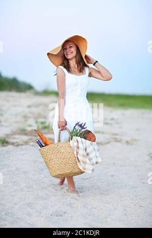 Junge Frau hält Picknickkorb mit Flasche Wein und Baguette Stockfoto