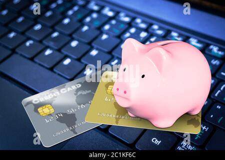 Pink Sparschwein auf der Oberseite der fiktiven Kreditkarten auf Computer-Tastatur zu illustrieren Kreditklemme, finanzielle Kreditaufnahme, Online-Shopping und Ersparnisse c Stockfoto
