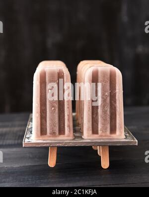 Hausgemachte Schokolade Eis lolly in einer Form, auf einem schwarzen Hintergrund mit Kopie Raum aus Holz Stockfoto