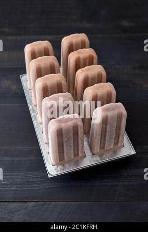 Eis am Stiel. Schokolade Hausgemachtes Sorbet in Kunststoff Form auf einem schwarzen Holz- hintergrund Kopie Platz für Text. Ansicht von oben Stockfoto