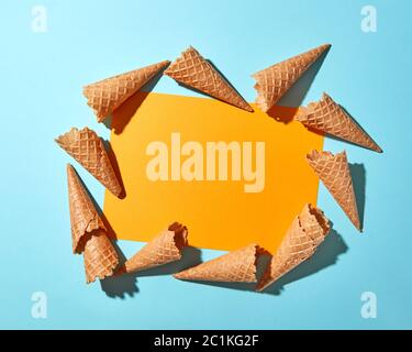 Das Muster der Waffel Eistüten Postkarte mit gelben Karte in der Mitte auf einem Pastell-blaue Papier. Flach. Stockfoto