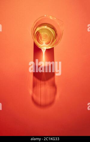 Transparentes Wasser in ein Glas mit Reflexionen und Schatten auf rotem Papier Hintergrund Stockfoto
