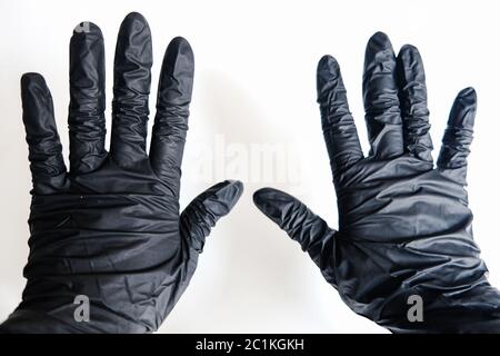 Nahaufnahme von zwei Händen in schwarzen Handschuhen auf weißem Hintergrund. Stoppen Sie die Verbreitung von Viren und verhindern Sie Krankheiten. Bleiben Sie zu Hause sicher und schützen Sie sich Stockfoto