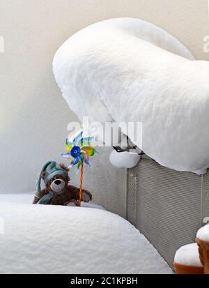 Jimmy sitzt im Schnee mit einem bunten Windrad. Stockfoto