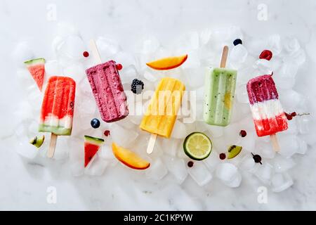 Verschiedene Eis auf einem Stick und verschiedene Stücke von Obst und Beeren auf Eiswürfel. Flach Stockfoto