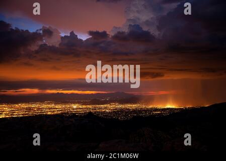 Die Lichter der Stadt Tucson leuchten in der Dämmerung während eines Vollmonds im September während einer späten Monsunbedratung am Windy Point in den Santa Catalina Bergen, Mo Stockfoto