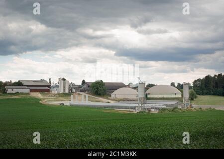 Dunkle Wolken über einem Bauernhof mit Biogasanlage und mehreren Bauernhäusern Stockfoto