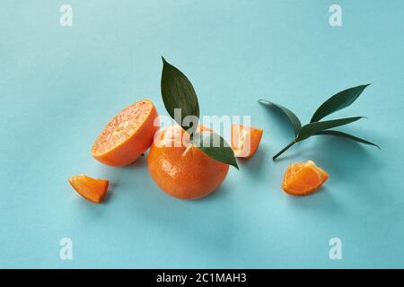 Exotische Zitrusfrüchte mit grünen Blättern auf blauem Papierhintergrund. Stockfoto