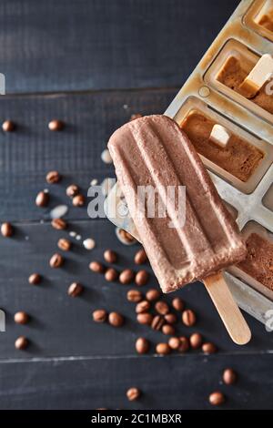 Klassische Eisform-Set Eisfroster für hausgemachte Schokoladeneis Lolly im Sommer über dunklem Holzhintergrund, Draufsicht Stockfoto