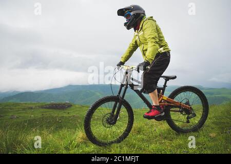 Ein Mann in einem Berghelm mit dem Mountainbike fährt um die schöne Natur bei bewölktem Wetter. Bergab Stockfoto